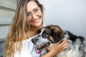 Svenja, Vorstand vom Tierschutzverein, lacht in die Kamera und streichelt einen Hund