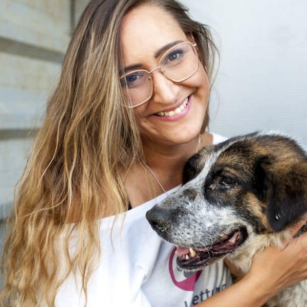 Svenja, 1. Vorsitzende des Vereins, kuschelt mit einem Hund und lacht in die Kamera