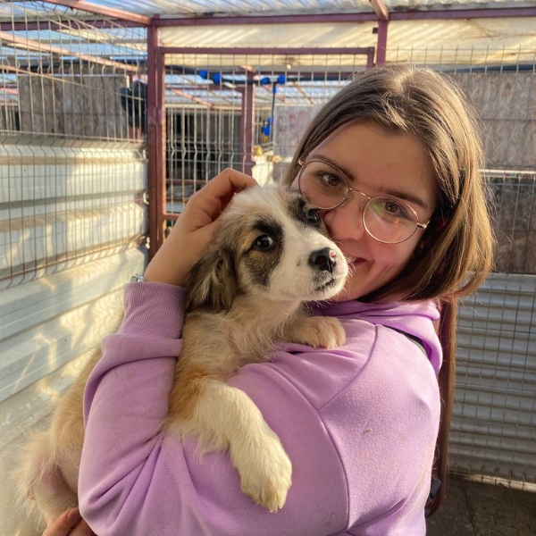 Frau mit Hund schaut in die Kamera.