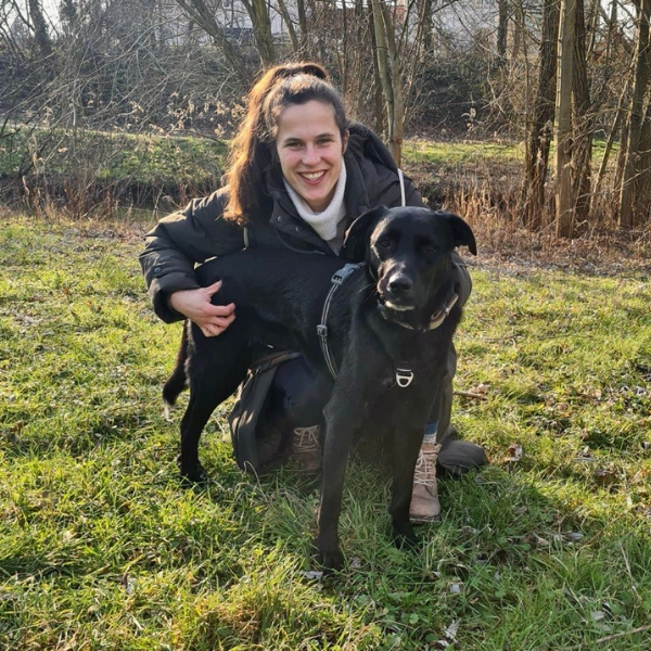 Frau mit Hund schaut in die Kamera.