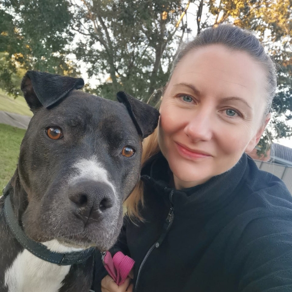 Frau mit Hund schaut in die Kamera.