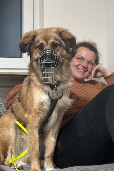 Rüde Aperol sitzt neben seinen Menschen auf dem Sofa.