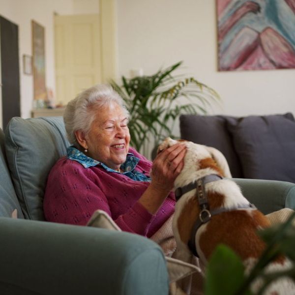 Ältere Frau auf der Couch mit einem Hund.