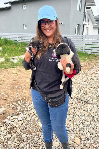 Frau mit einem Welpen und einem Kitten auf dem Arm