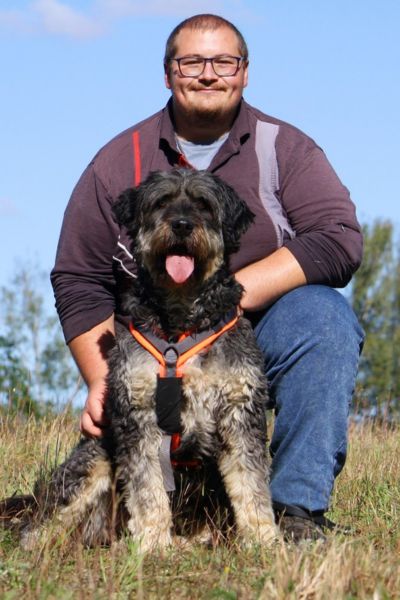 Cora sitzt an ihren Pfleger gekuschelt.