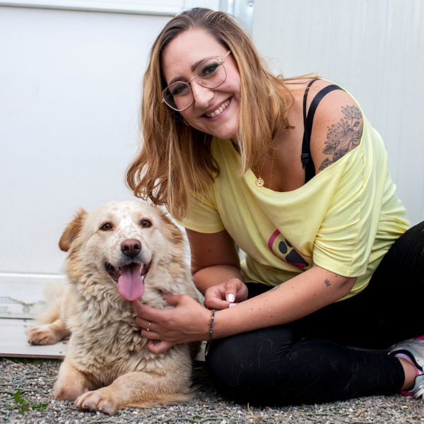 Frau mit Hund schaut in die Kamera.