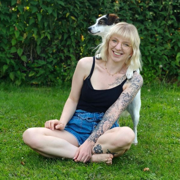 Frau mit Hund sitzend auf dem Rasen und schauen in die Kamera