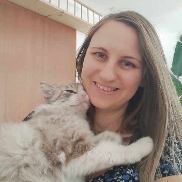 Frau mit Katze auf dem Arm schaut in die Kamera