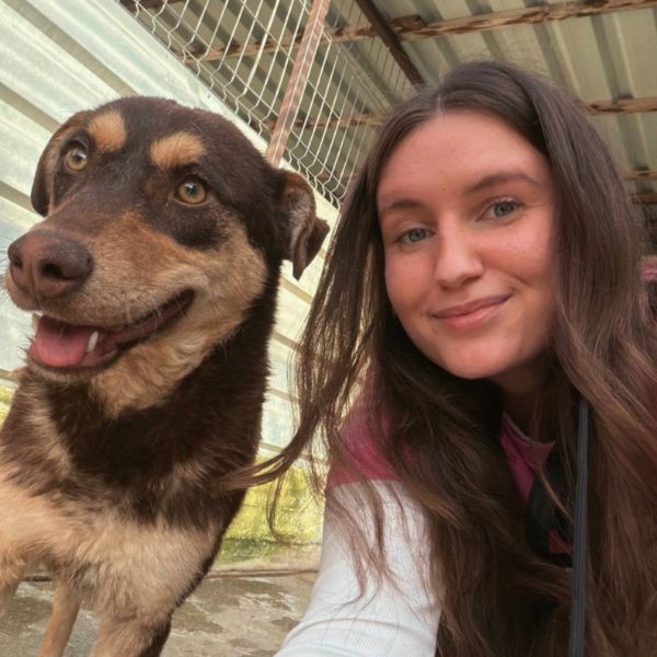 Frau mit Hund schaut in die Kamera
