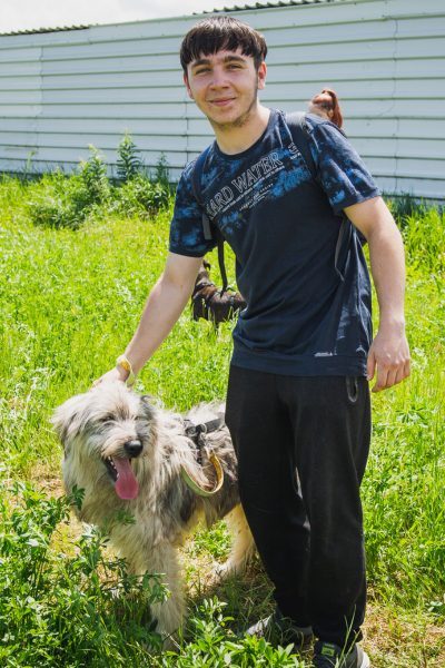 Junge streichelt einen Hund auf der Wiese vorm Tierheim