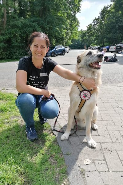 Eine Frau kniet neben einem großen, hellen Hund