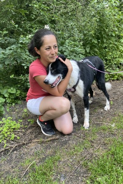 Eine Frau kuschelt mit einem schwarz-weißen Hund