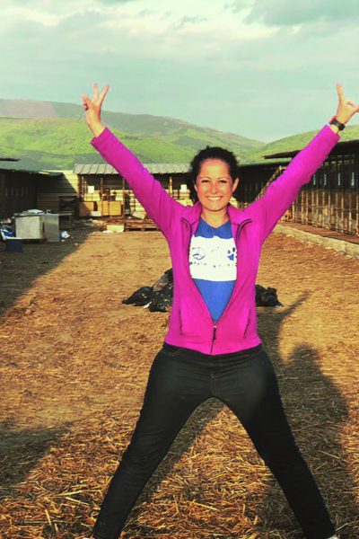 Eine Frau reckt die Arme in die Luft und strahlt in die Kamera