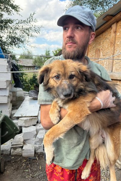 State hält einen braunen Hund im Arm