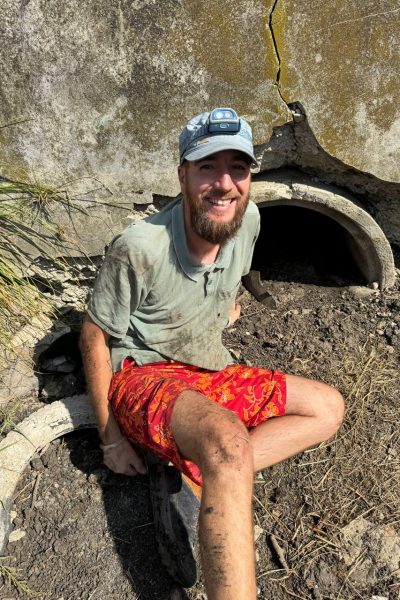 State sitzt auf einer Baustelle und lächelt glücklich in die Kamera