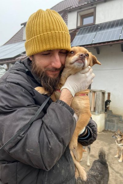 State kuschelt mit einem kleinen, hellbraunen Hund