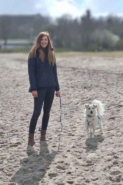 Ein Hund und eine Frau stehen am Strand.